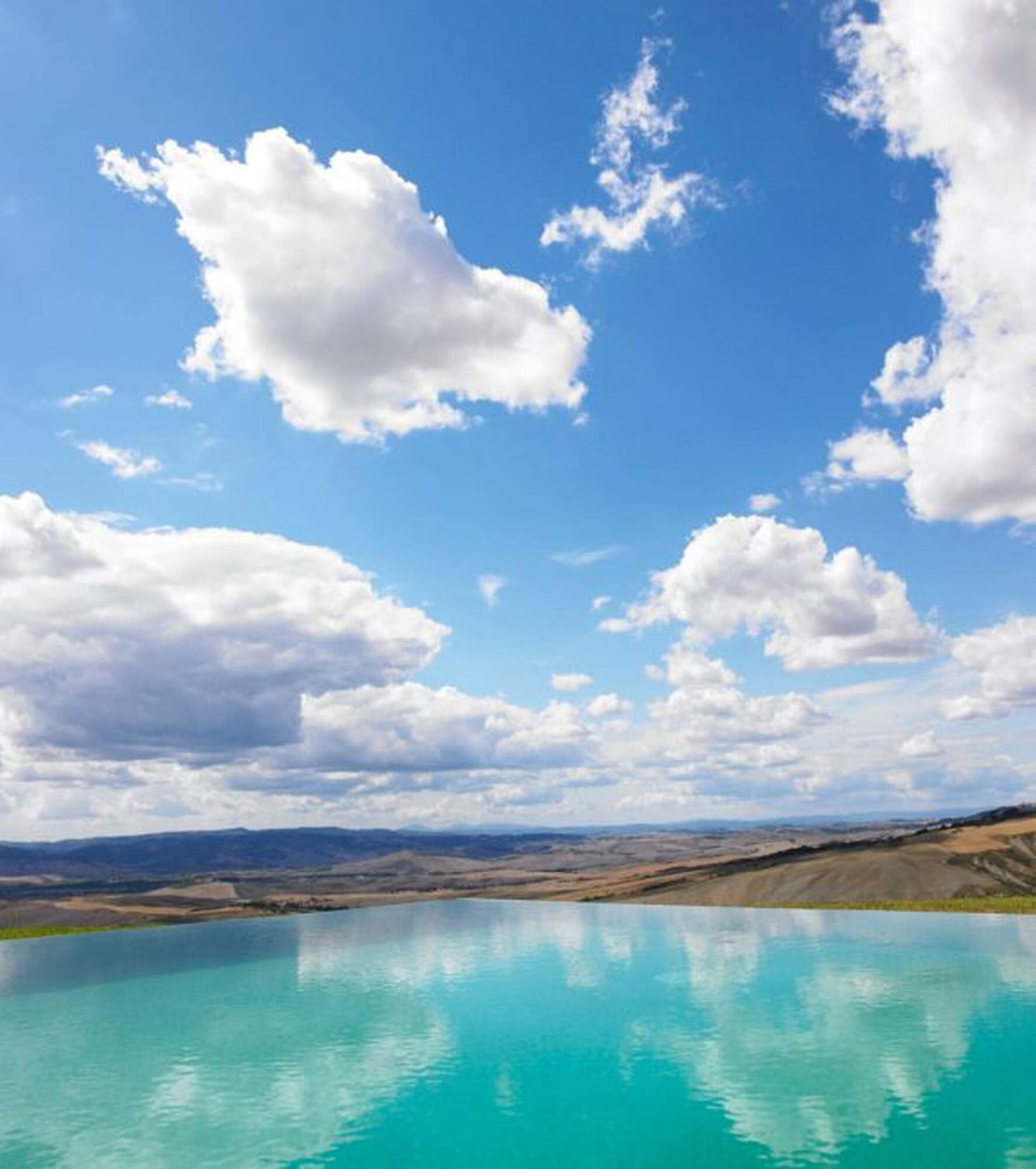 scenic image of blue skies with fluffy clouds over an aqua blue lake.