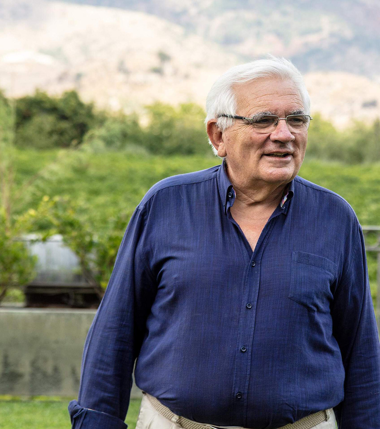 Man wearing blue shirt standing in a vineyard.
