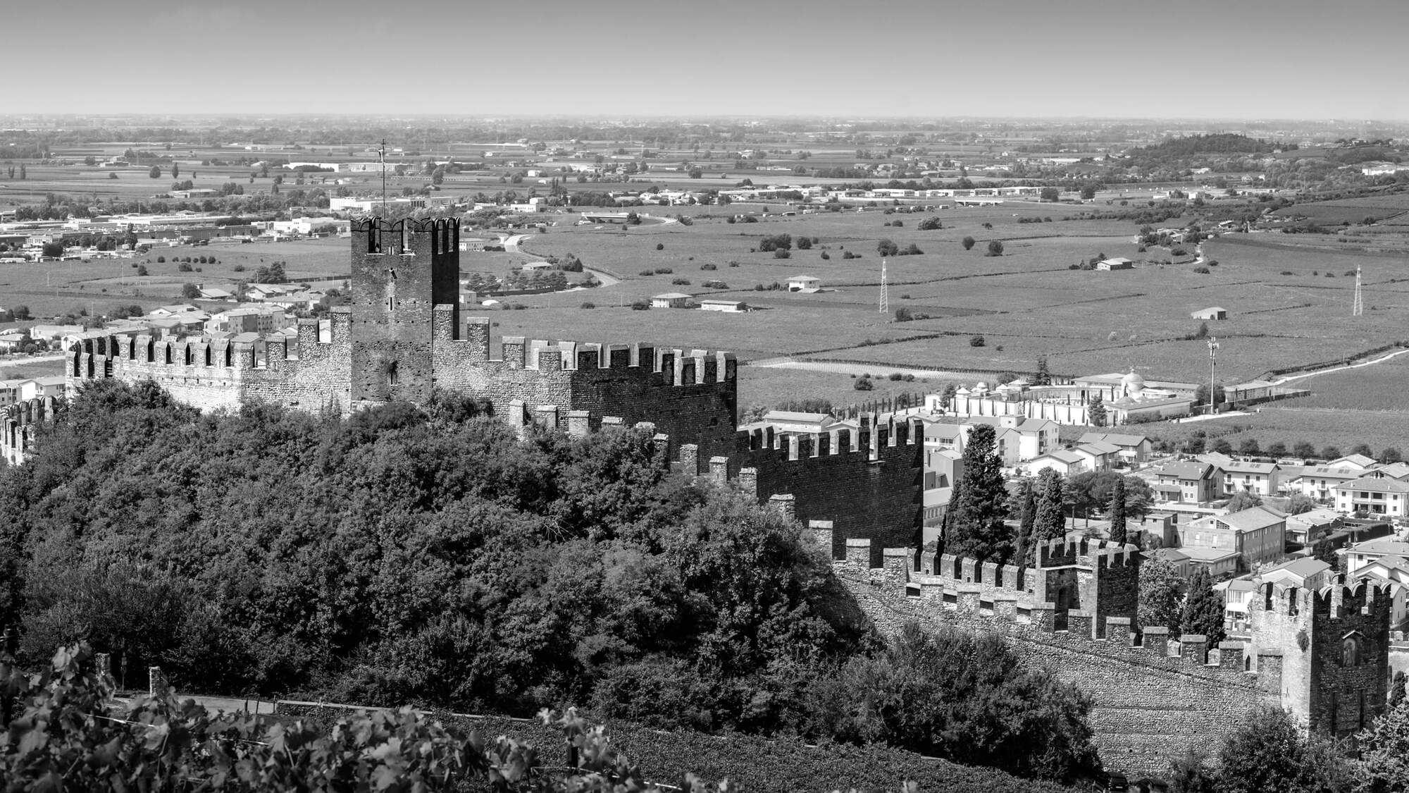 black and white image of a Castle in Italy overlooking a small town.