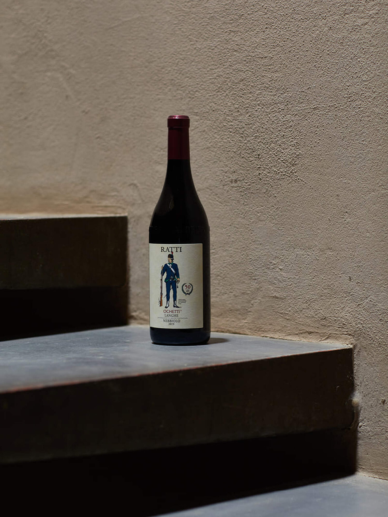 A bottle of Ratti wine on a concrete stairway.