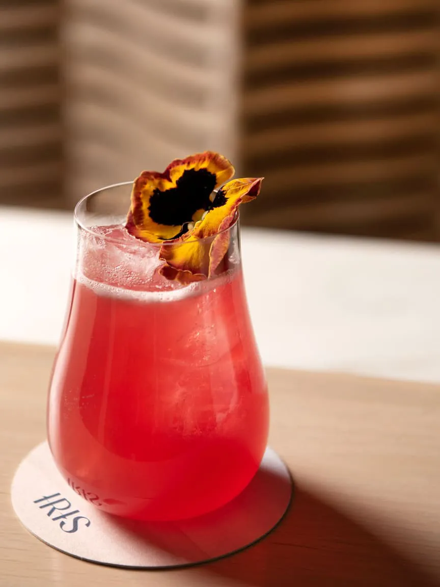 Pink cocktail drink with a flower garnish