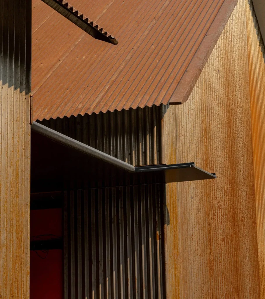 Close-up of modern architecture featuring rust-colored corrugated metal roofing and textured walls.
