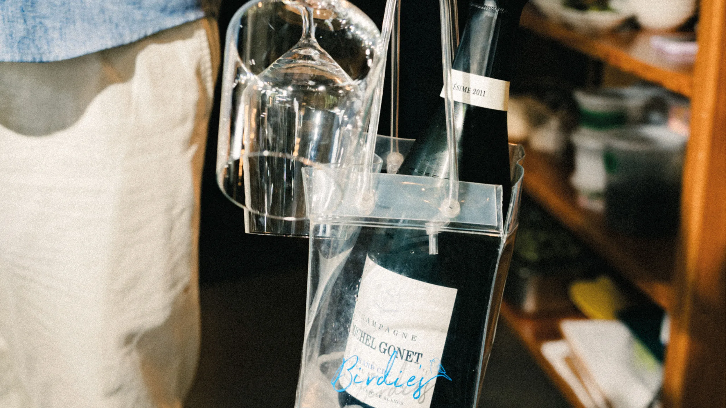 Champagne bottle and upside-down wine glass in a clear carrying case.