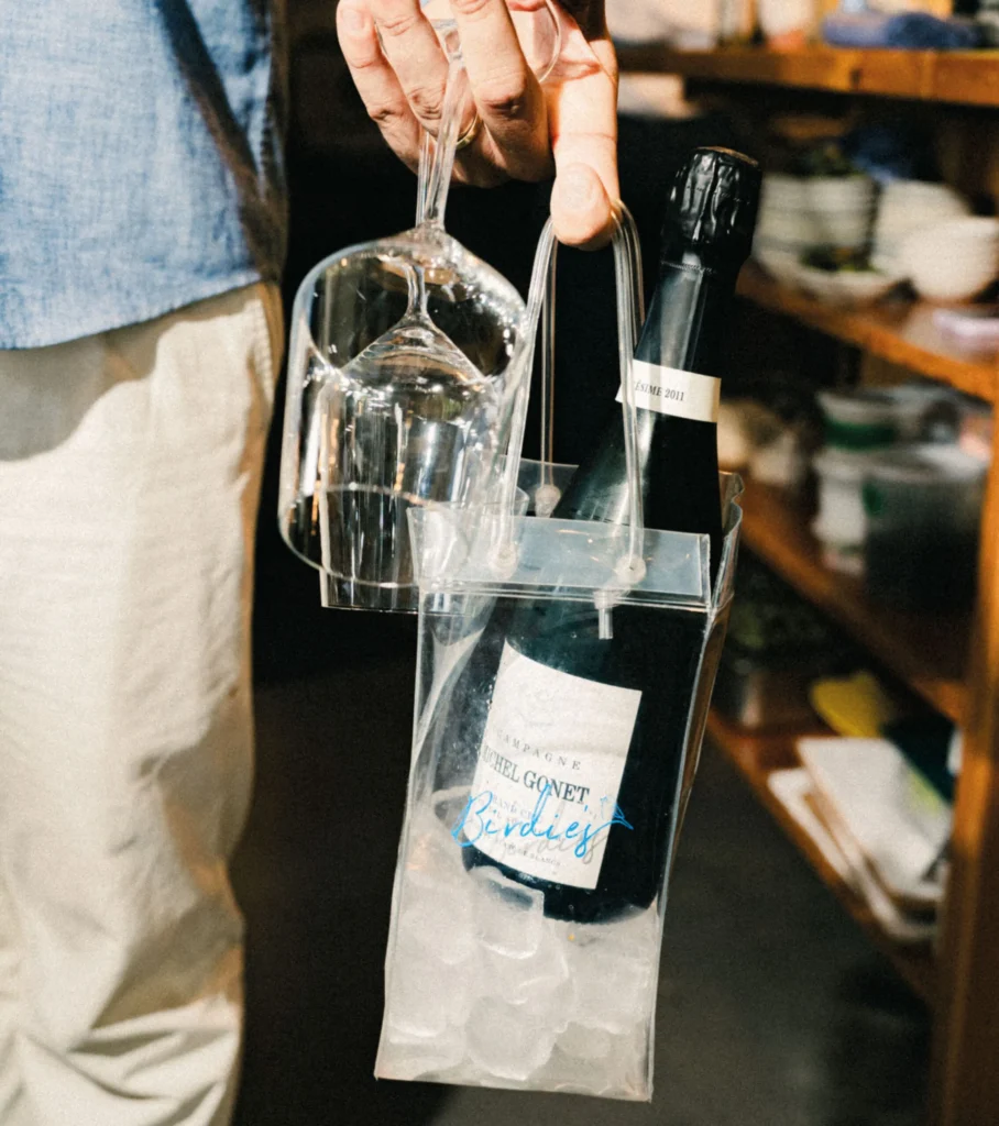 Champagne bottle and upside-down wine glass in a clear carrying case.