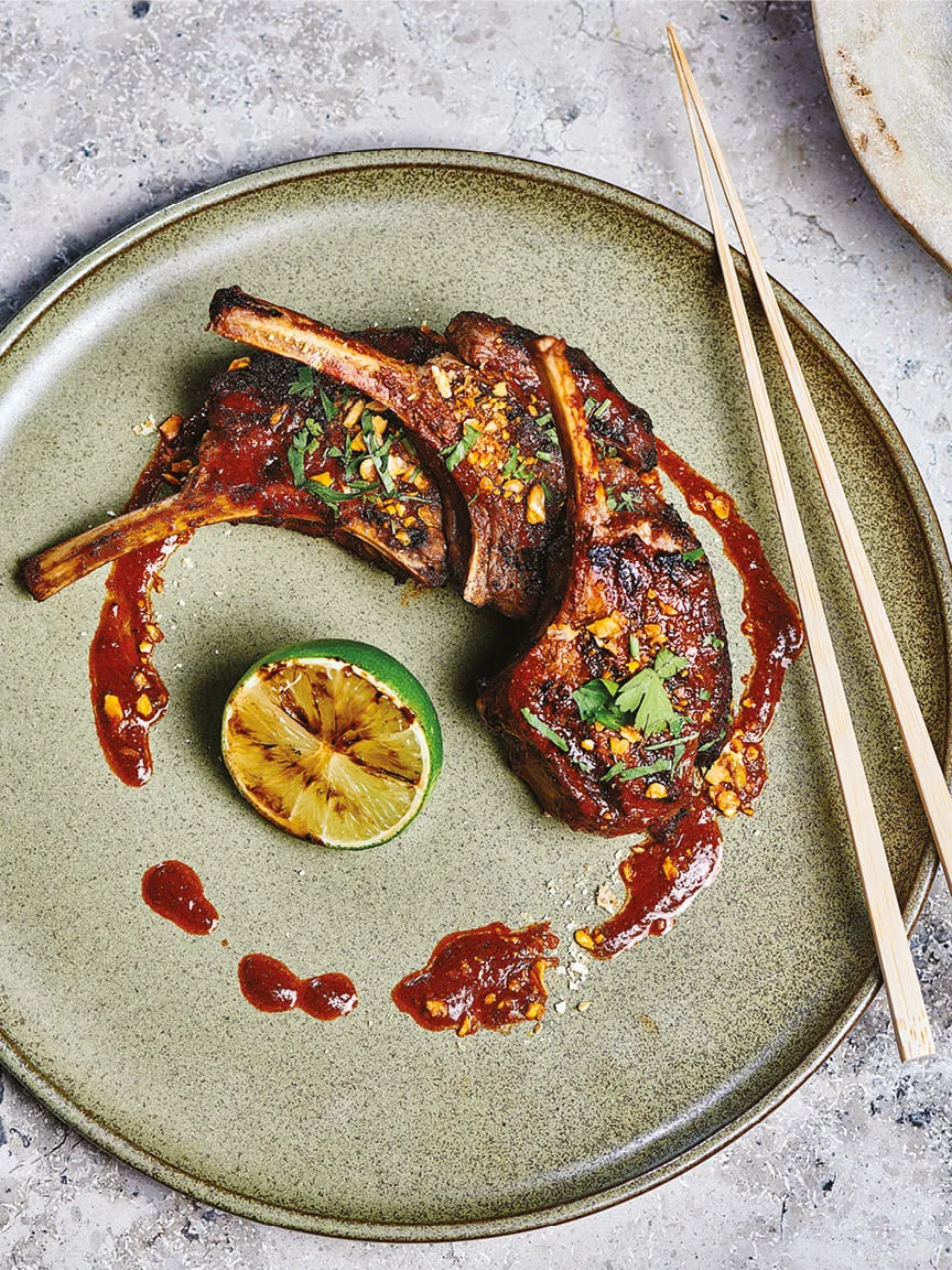 Glazed lamb chops with charred lime and chopsticks on a green plate