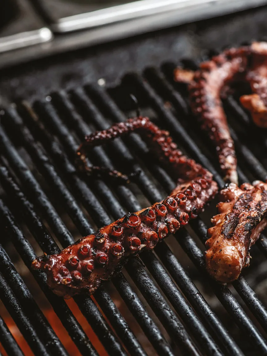 Octopus tentacles cooking on a grill