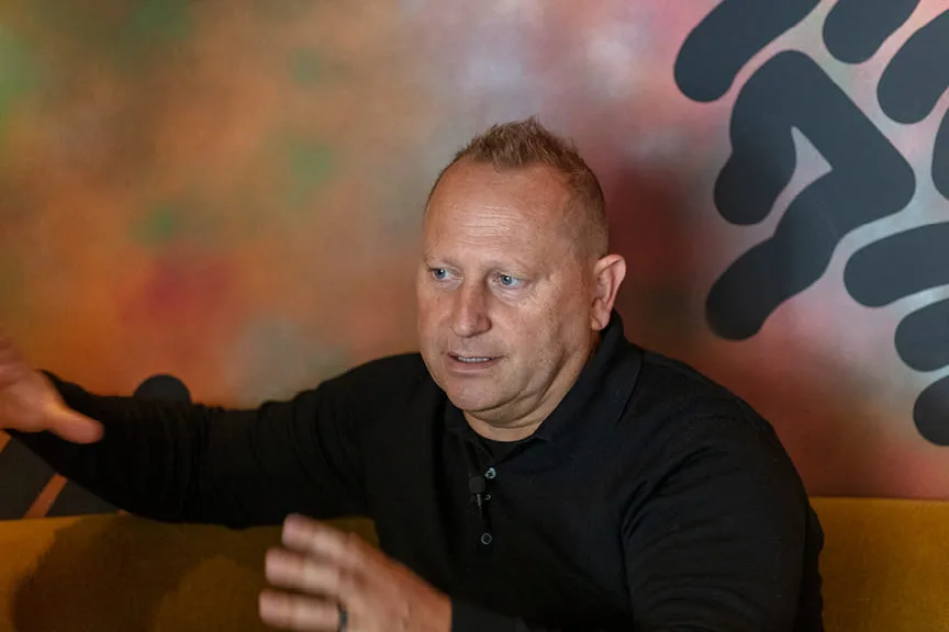 Kurt Zdesar seated, talking, in front of a colourful mural at Chotto Matte