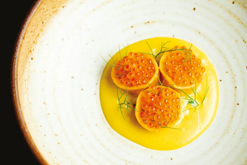 Gourmet dish topped with orange fish roe and fresh herbs.