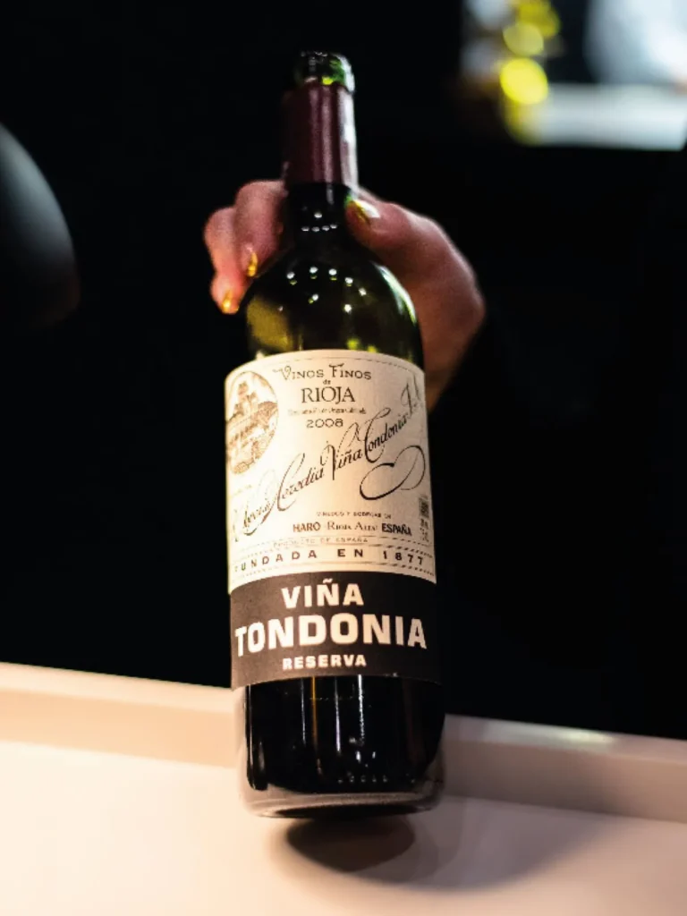Bottle of Viña Tondonia Reserva Rioja wine being held against a dark background.
